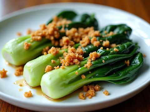Bright green garlic bok choy halves topped with golden fried garlic on a white plate